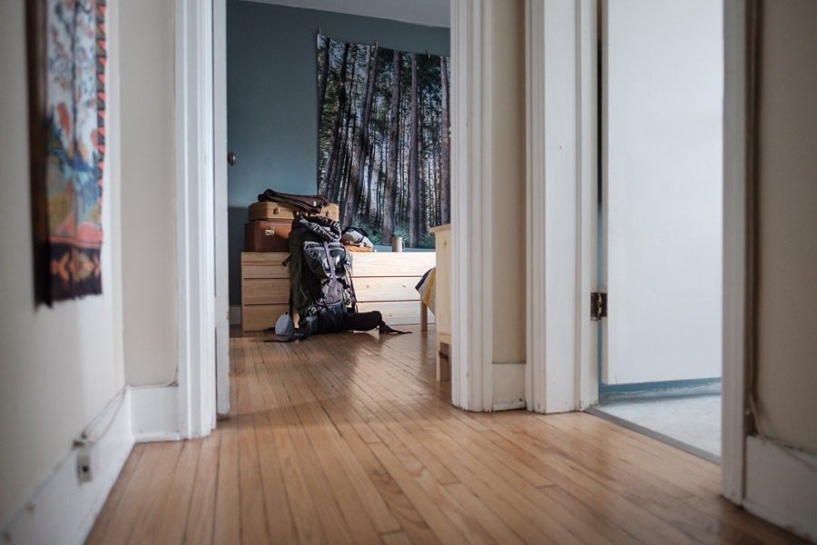 A packed backpack leans against the wall, ready to leave home behind.