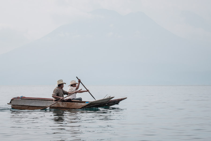 Two jovial Mayan men commuting in traditional Cayucos - a unique form of dugout canoes.