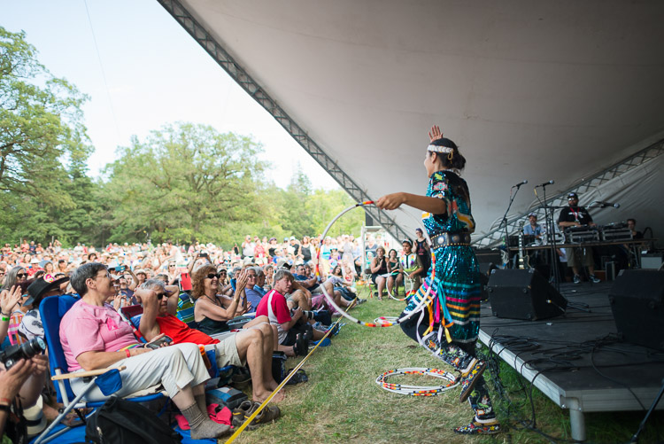 Shanley Spence walks the thin line that separates the crowd from the stage, hoop dancing to the rhythms of DJ Shub.