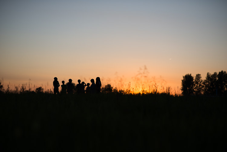 Children gather, making new friends as the sun dips below the prairie horizon.